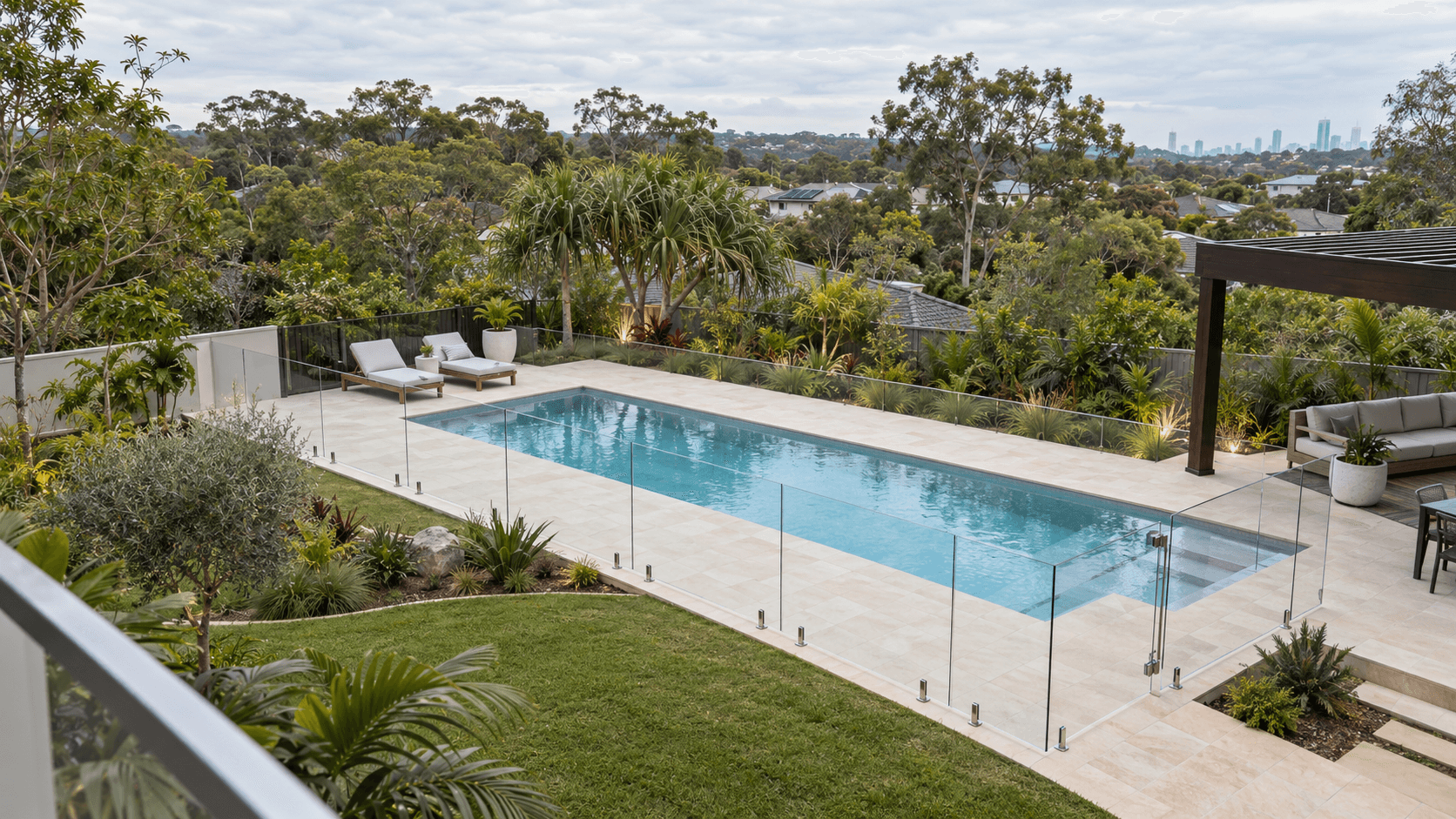 A broad backyard pool with glass fencing set into the landscape